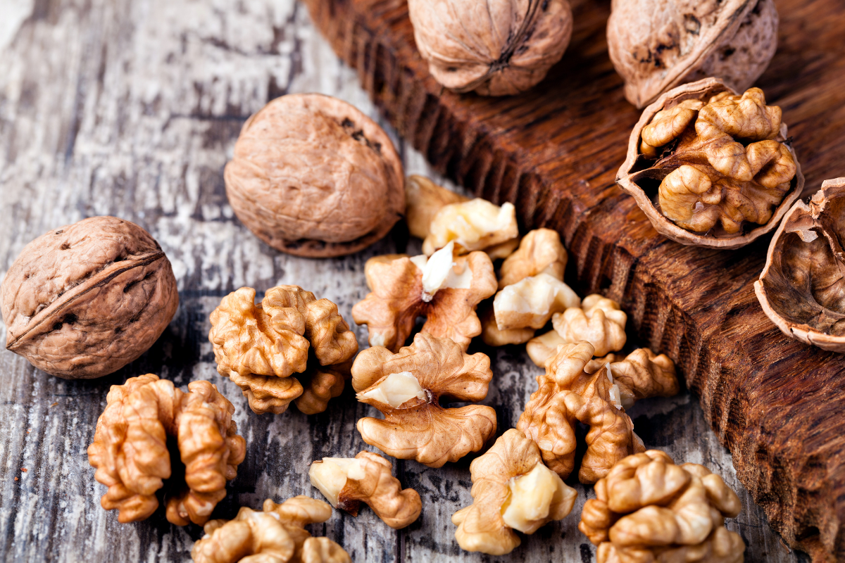 Shelled walnuts and whole walnuts on wood.