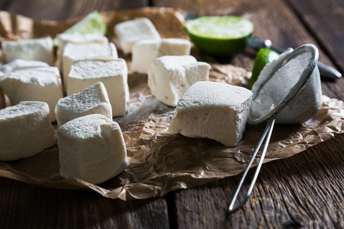 Homemade marshmallows powdered sugar dusted with a strainer, and lime at the background.