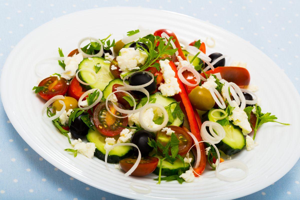 A fresh shopska salad with cucumbers, tomatoes, peppers, olives, onions, and feta cheese.