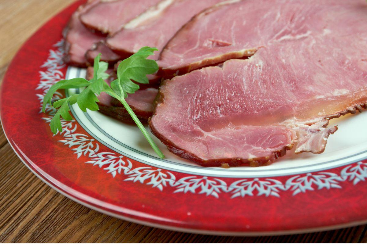 A plate of Icelandic hangikjöt, smoked lamb served with a white sauce and garnished with onions and red shavings