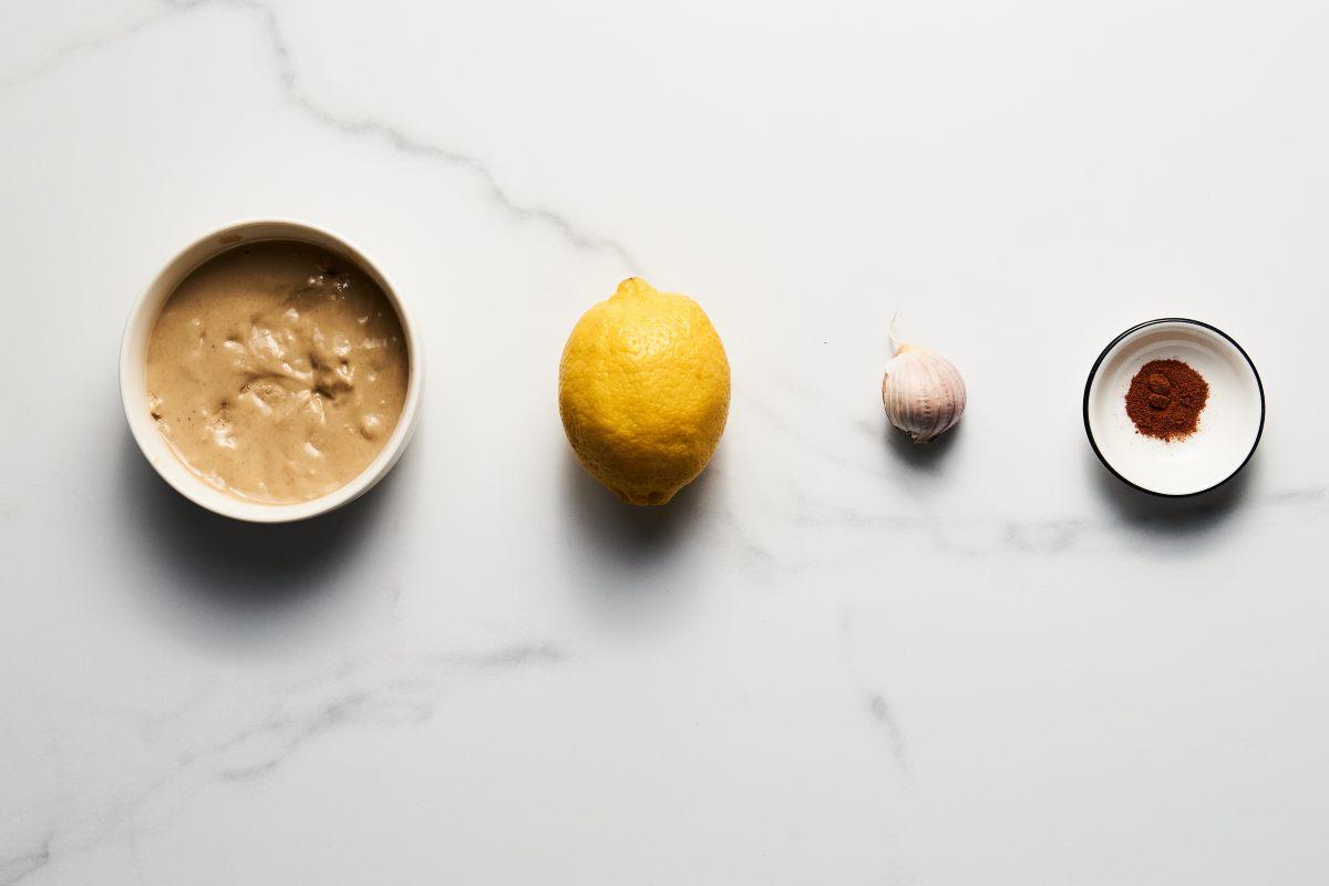 Ingredients to prepare tahini tarator, tahini, lemon, garlic and cumin.
