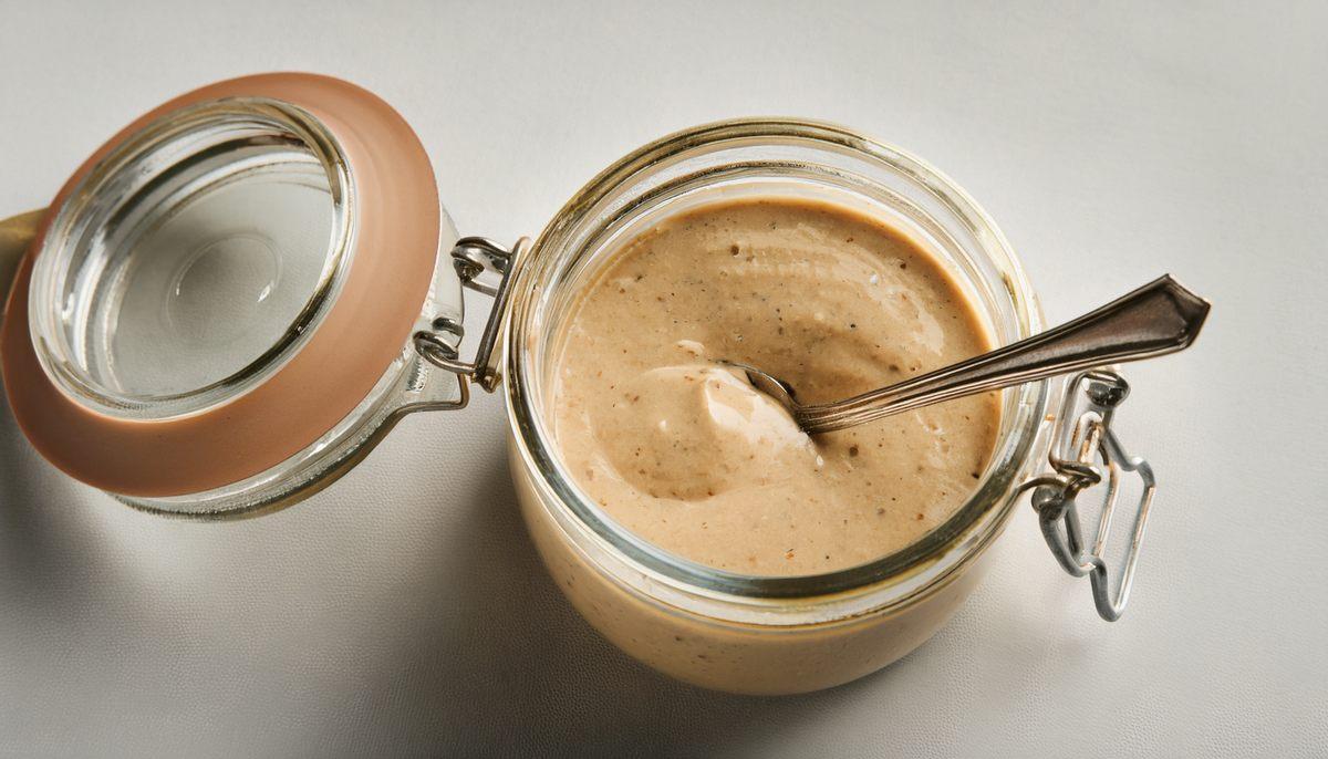 Tahini tarator sauce in a glass jar, image edited with AI.