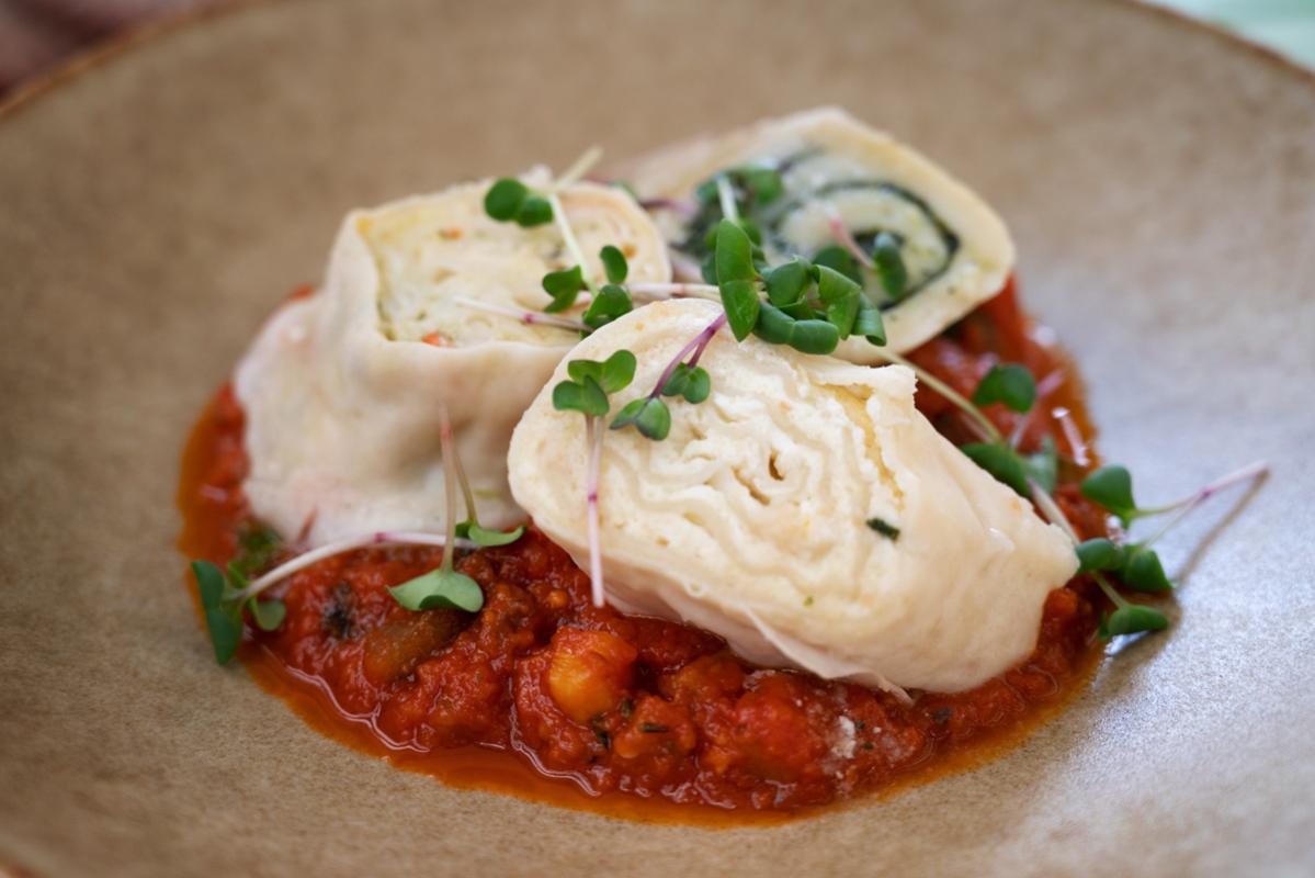 Traditional Slovenian štruklji, consisting of rolled dumpling filled with cheese and a tomato based sauce.