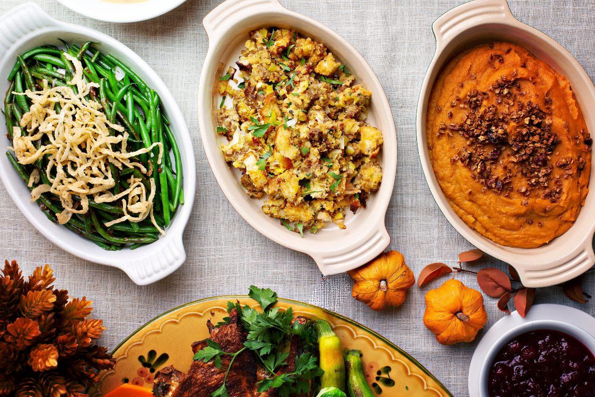 Overhead view of Thanksgiving side dishes including green beans, stuffing, and sweet potato casserole with nuts.