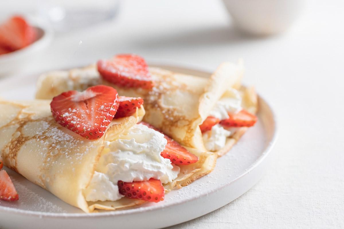 A plated serving of strawberries and cream crepes.