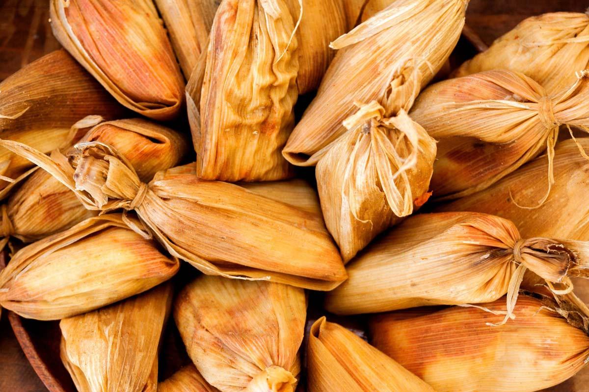 Guatemalan chuchitos wrapped in golden corn husks and piled together.