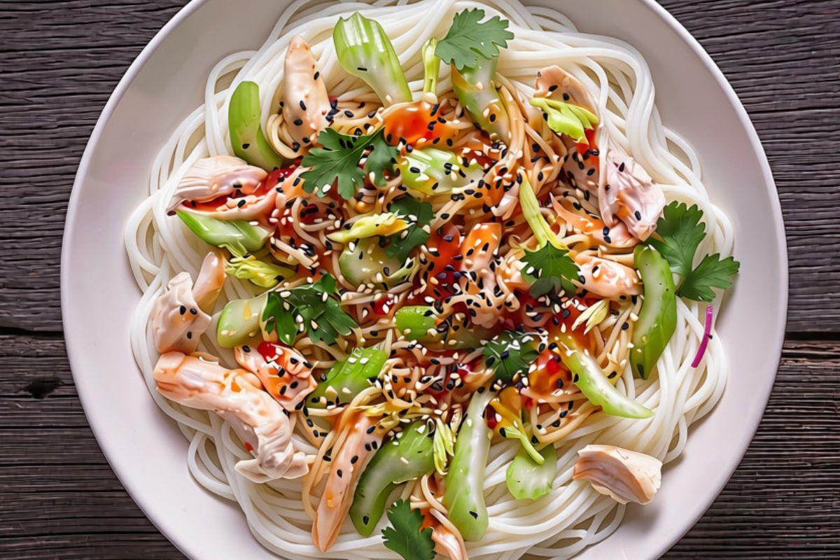 Thai chicken noodle stir-fry with rice noodles, chicken, baby bok choy, cilantro, green onions, sesame seeds, and savory sauce on a white plate.