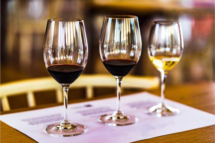Three wine glasses ready for a wine tasting, two of the with red wine and ona with white wine.