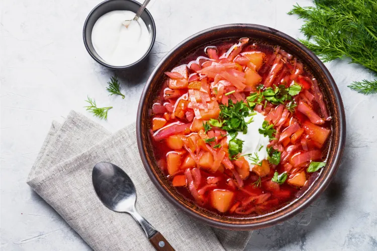 Traditional Ukranian borscht soup in a bowl on gray stone.