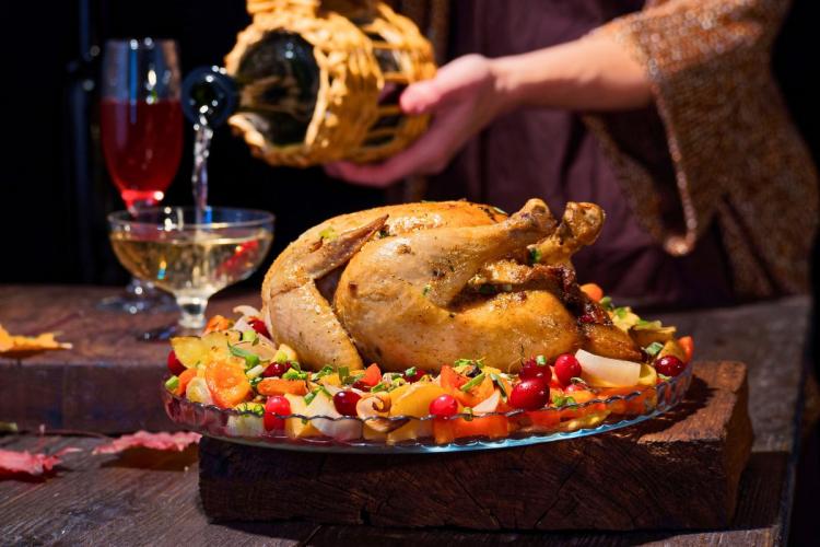 A roast chicken on a serving plate and white wine.