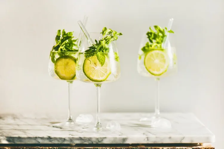Three glasses of mint lime spritzes with lime slices and fresh mint on a marble surface.