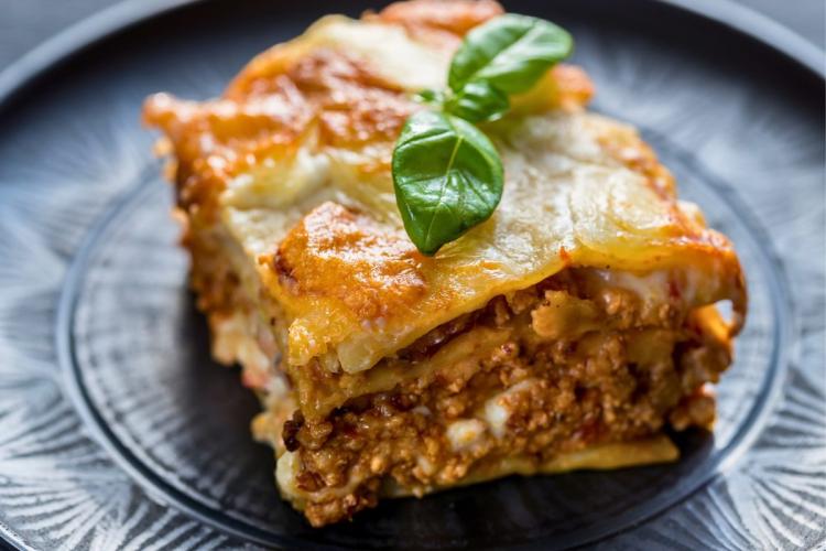 A portion of lasagna Bolognesa on a dark plate.