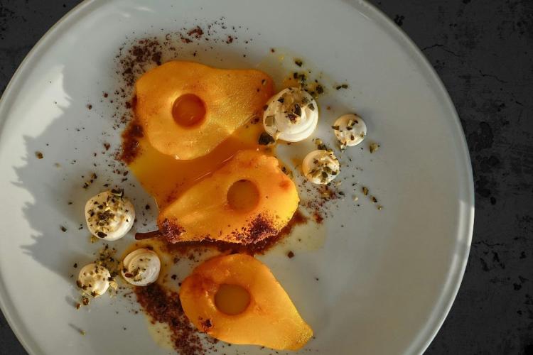 Three poached pears in a gourmet presentation, with cream and cinnamon.