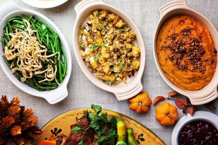 Overhead view of Thanksgiving side dishes including green beans, stuffing, and sweet potato casserole with nuts.