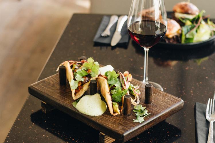 Mexican tacos with plenty of vegetables and fresh coriander accompanied by red wine.
