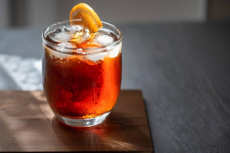 A glass of Vermouth with ice, decorated with a slice of orange.