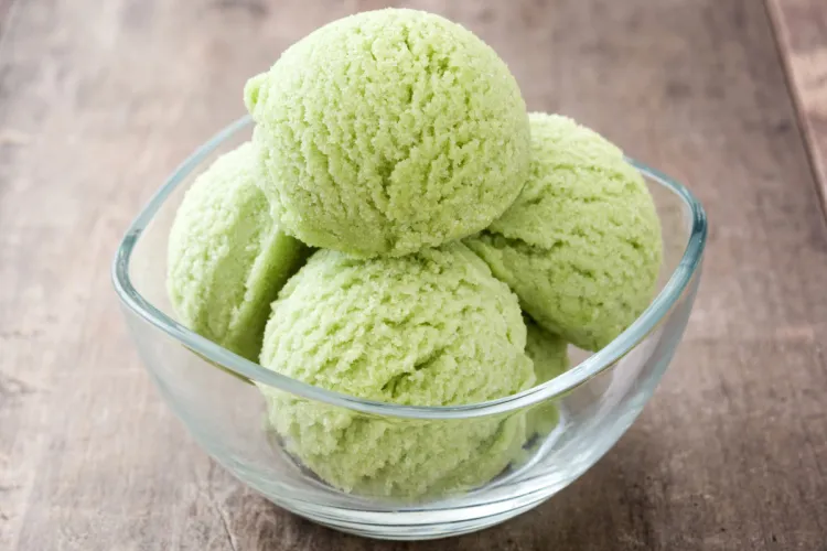 Four scoops of matcha ice cream in a glass bowl with a square rim.