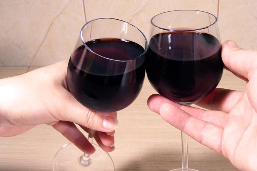 Hands holding red wine glasses and clicking.