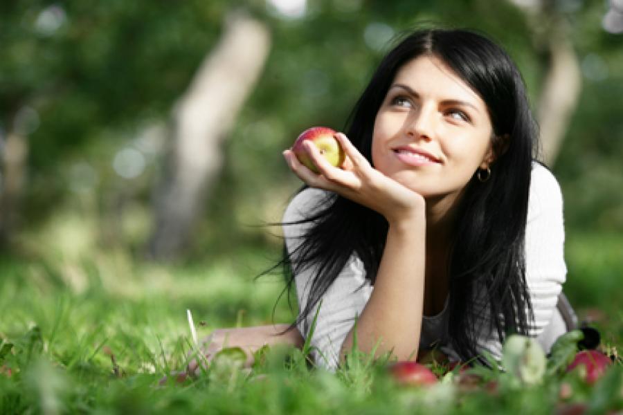 A young woman with an apple in the hand.