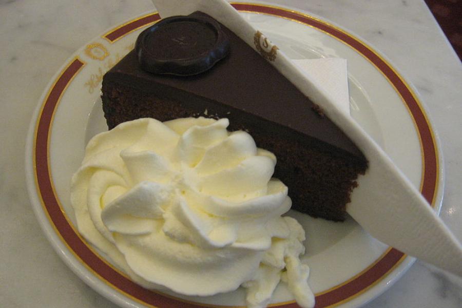 A piece of sacher torte served with whipped cream.