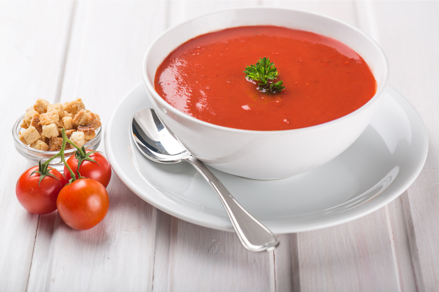 A bowl of tomato soup decorated with basil leaves.