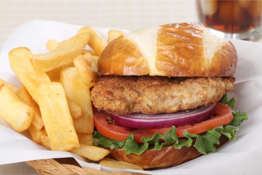 A breaded tenderloin sandwich accompanied of fries.