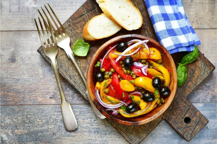 Peperonata, the classic Italian sauce, in a wooden bowl, rustic setting.