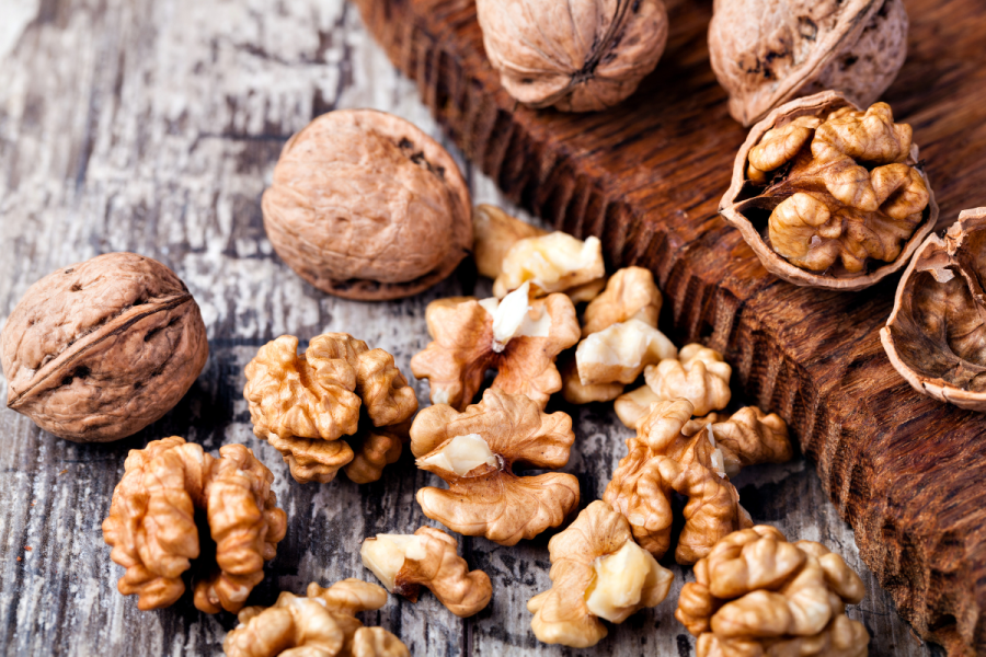 Shelled walnuts and whole walnuts on wood.