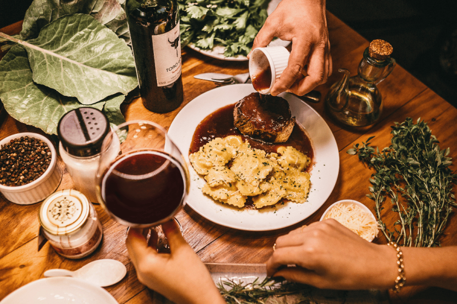 Food on top of the table and a glass with red wine.