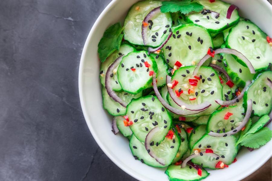 Asian cucumber salad with red onion and black sesame seeds.