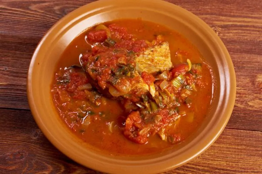 A plate of hraime, a traditional Libyan dish, featuring a piece of fish cooked in a thick, spicy tomato sauce.
