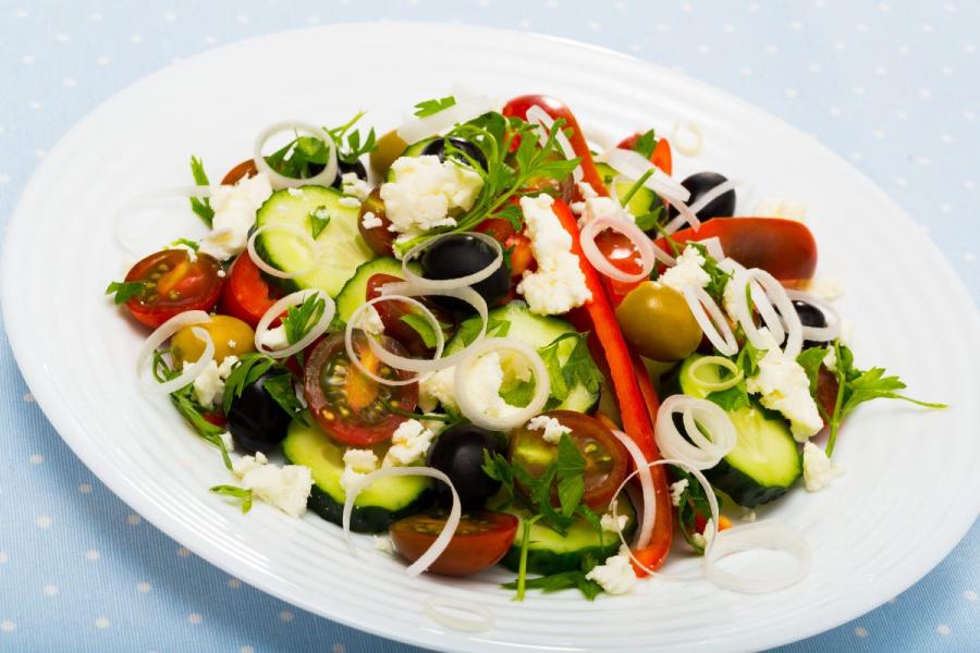 A fresh shopska salad with cucumbers, tomatoes, peppers, olives, onions, and feta cheese.