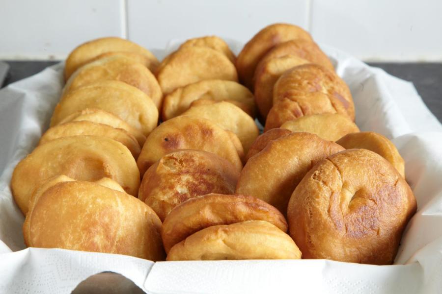 Tray of golden fried johnnycakes, neatly arranged on white paper, highlighting their crispy and appetising texture.