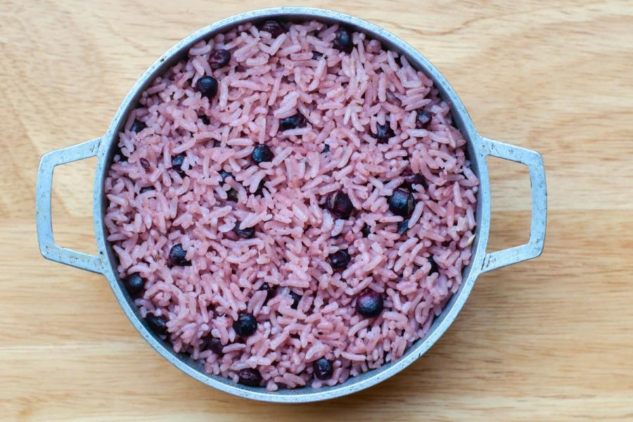 Rice cooked with dark pigeon peas, served in a rustic pot on a wooden surface