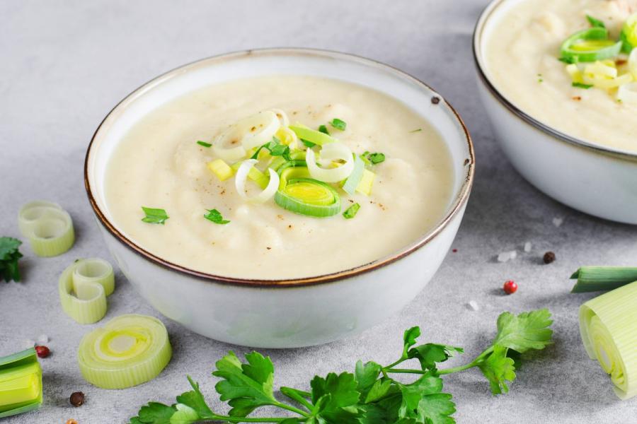 Creamy leek and potato soup garnished with fresh leeks and parsley.