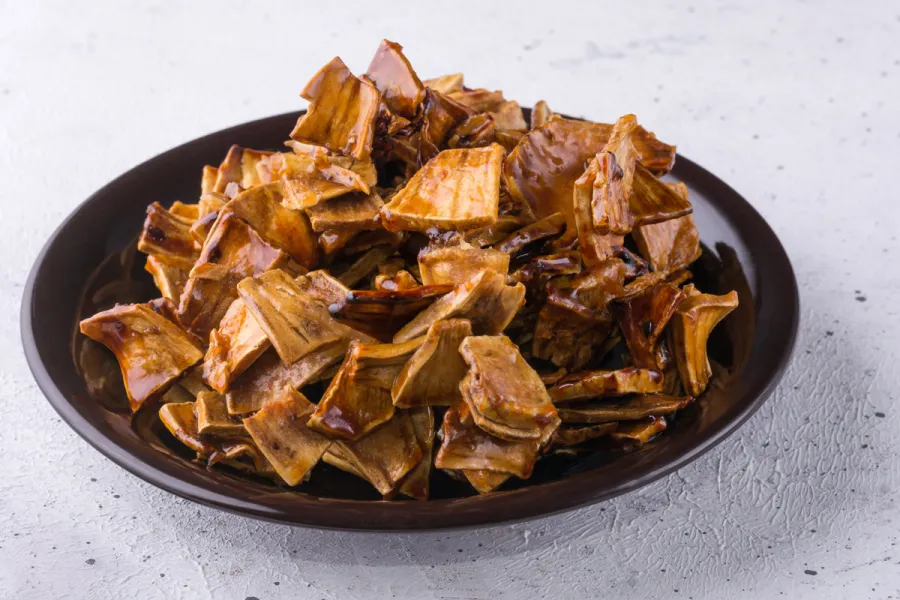 A plate with roasted breadfruit pieces mixed with sugar syrup.