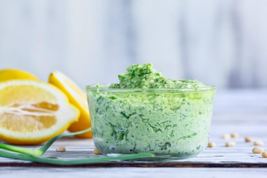 A recipient with garlic scape pesto surrounded by the fresh ingredients.