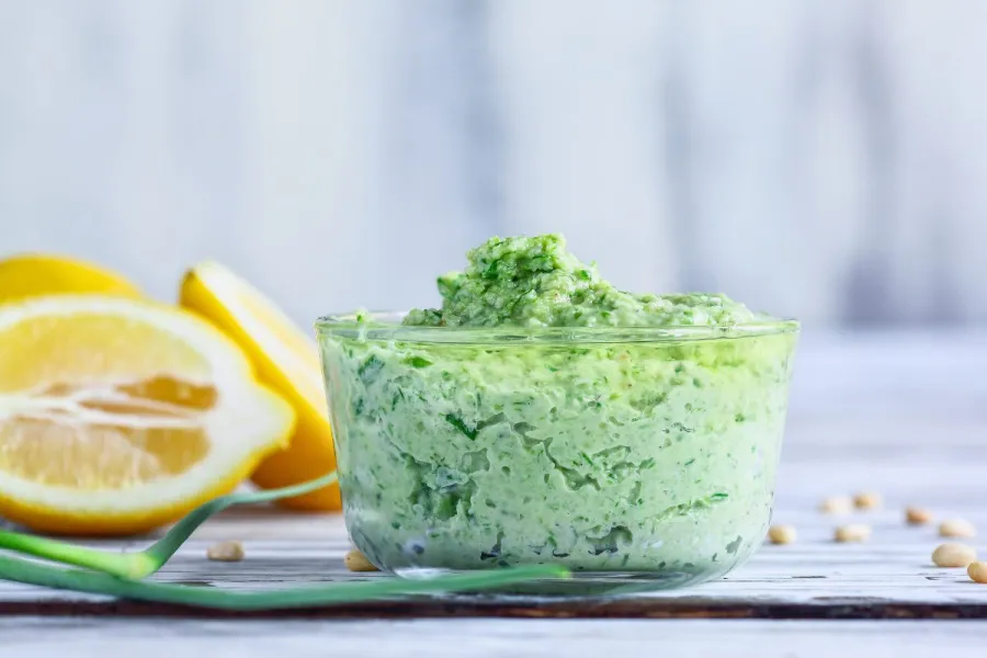 A recipient with garlic scape pesto surrounded by the fresh ingredients.