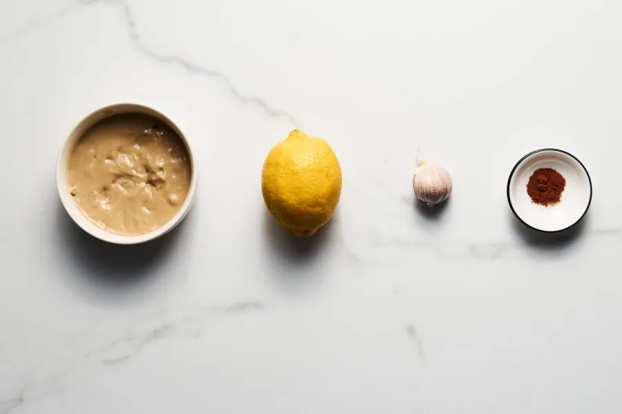Ingredients to prepare tahini tarator, tahini, lemon, garlic and cumin.