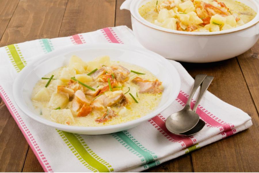 A plate of Cullen skink soup on a tea towel with a serving bowl of the same soup by the side.