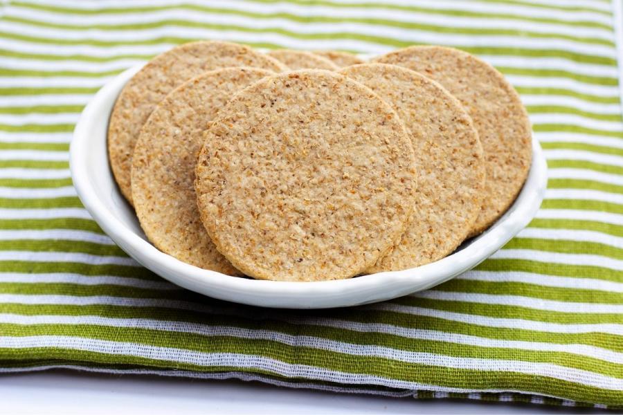 A bowl with oatcakes on a light green and white striped kitchen cloth.