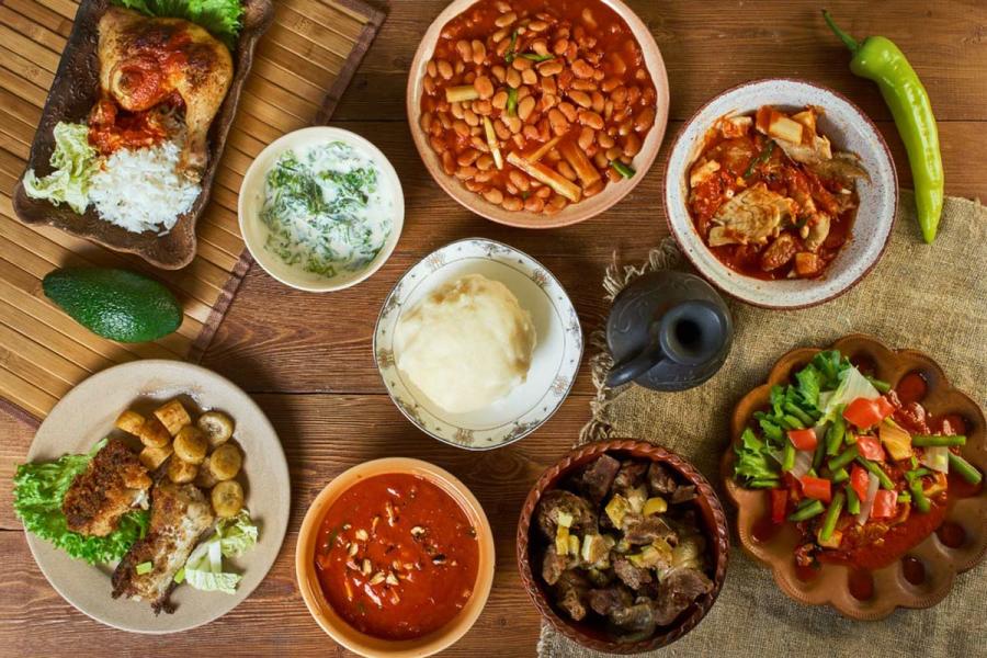 Assorted Congolese dishes including fufu, beans, rice, grilled meat, fish, and stews arranged on a wooden table.