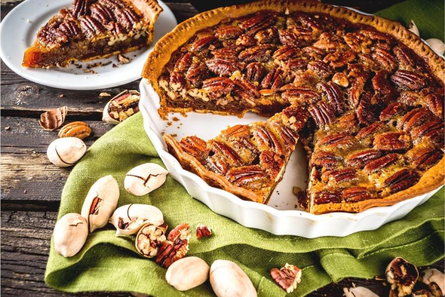 A pecan pie in a flan dish and a piece of cake on a plate.
