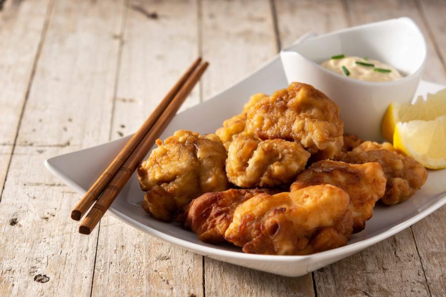 A plate of juicy, golden-brown chicken karaage served with lemon wedges and Japanese mayo, with chopsticks on the side, ready to eat.