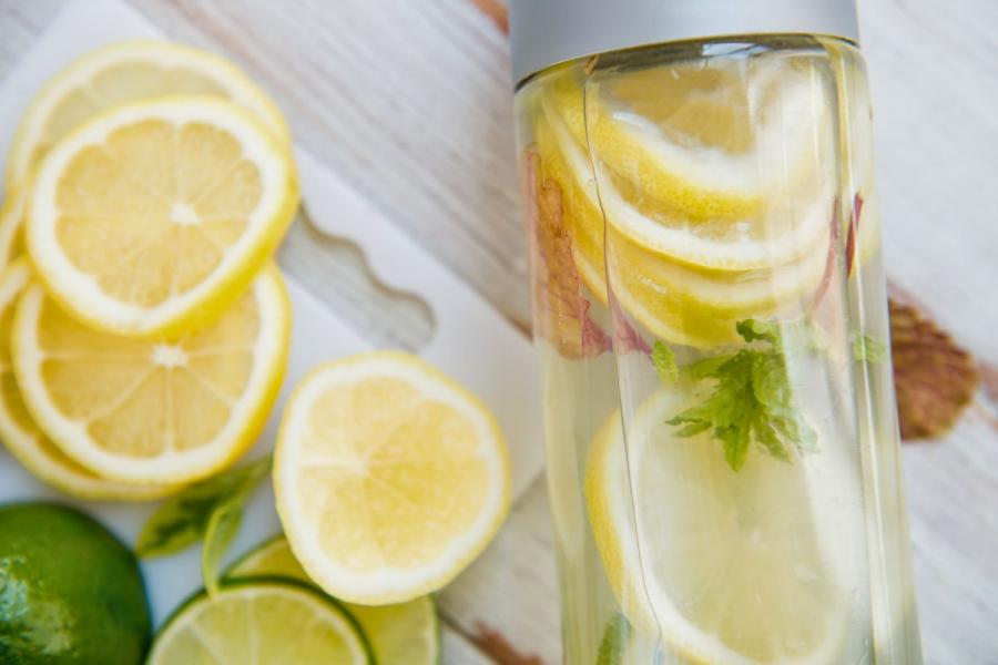 Water with lemon and mint in a clear bottle. On white. More lemon and a lime.